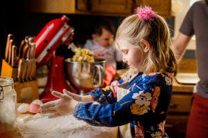girl making chocolate chip cookies with family in kitchen photographed by boston photographer nicole loeb